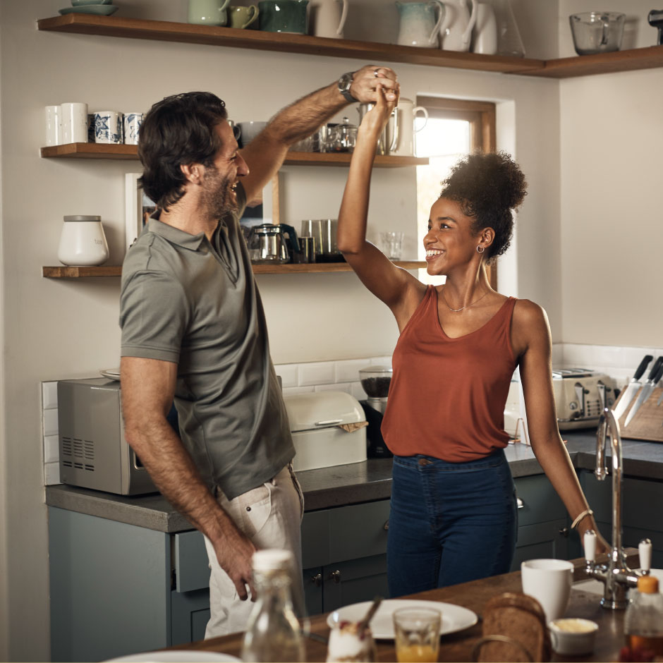 A happy couple dances in the kitchen