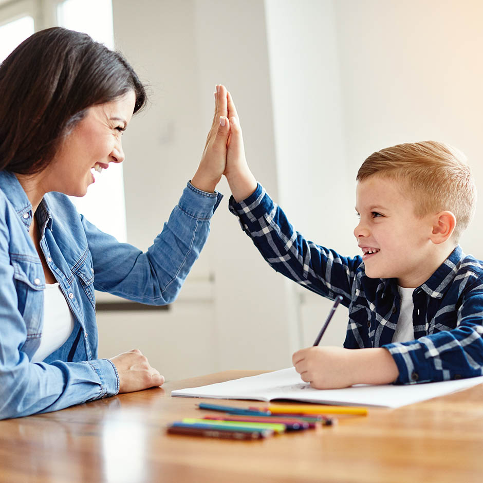 Young boy high-fiving teacher while learning